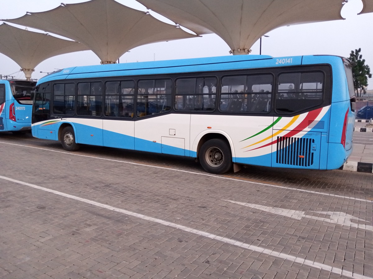 A Lagos BRT bus in the blue-and-white livery parked under the canopy of a bus terminal.